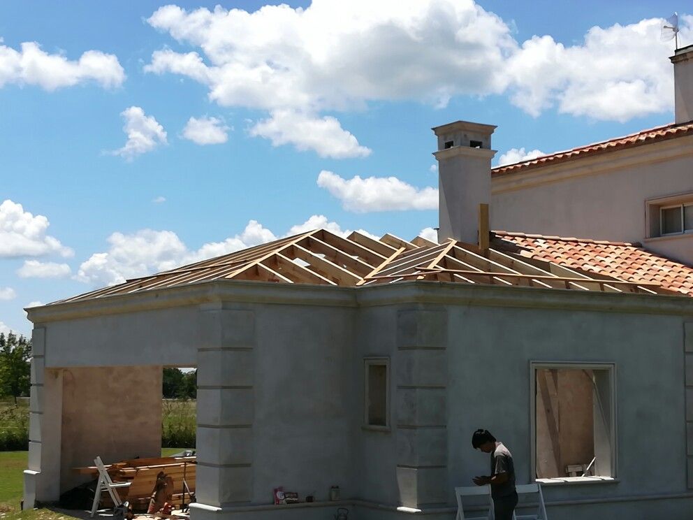Photo showing the house exterior after renovation with new wooden roof framing and red tiles.